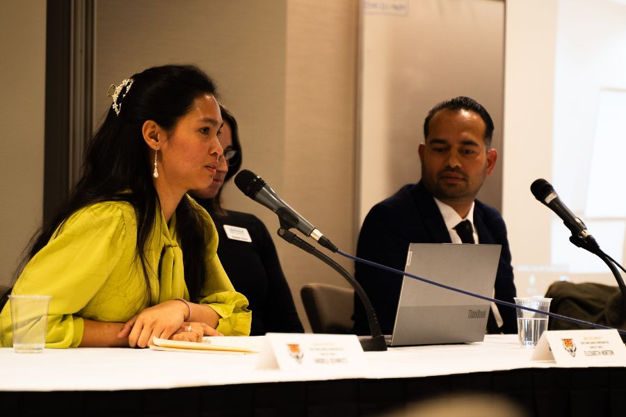 Marie Stango stands at the front of a high school classroom. Students in the class focus their attention toward her. One student is raising his hand.